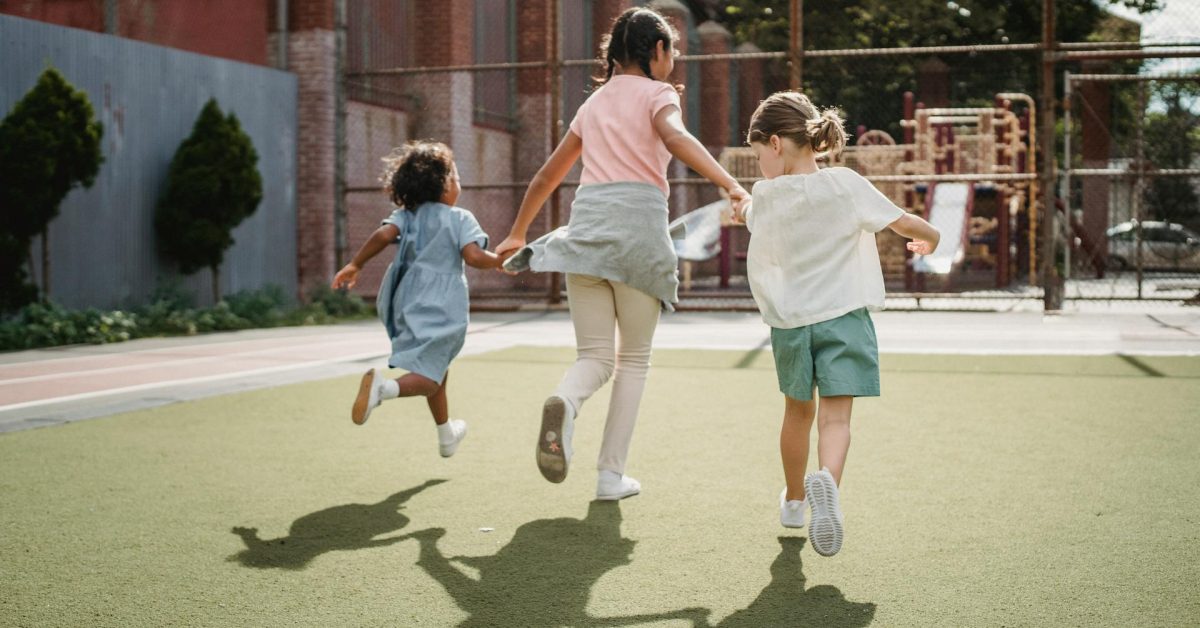 Picture of three children holding hands and running