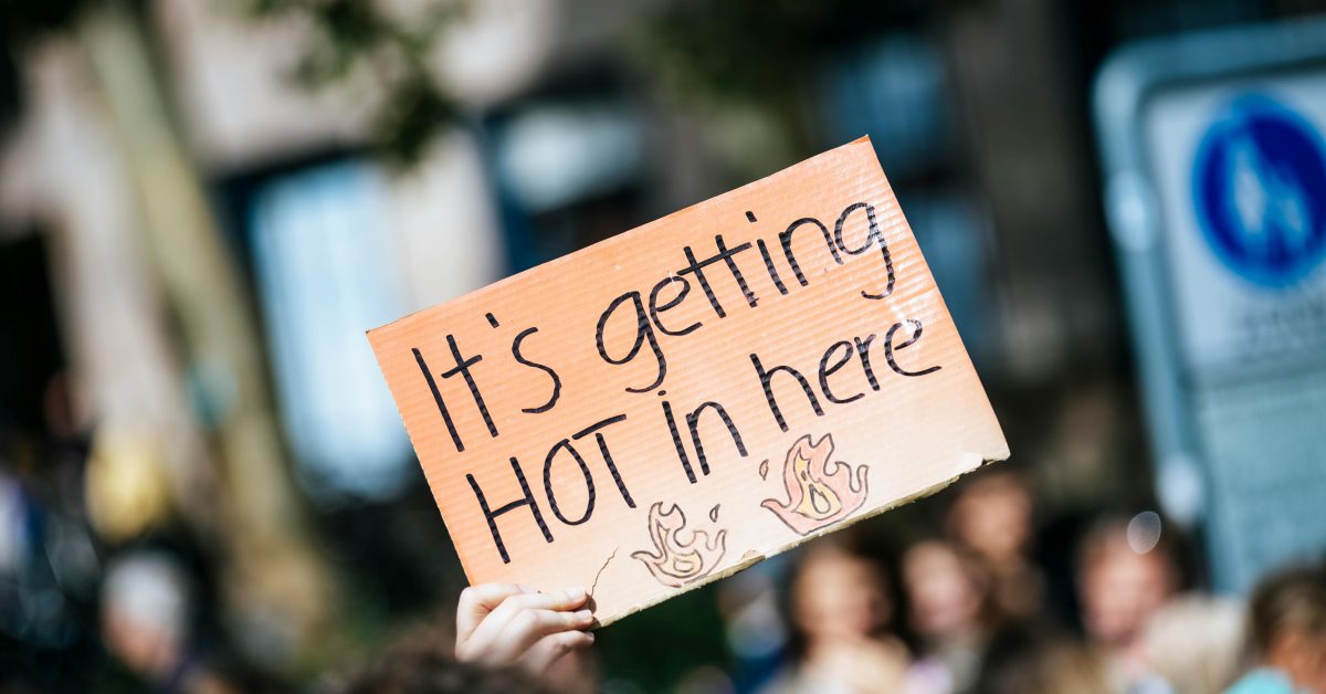 A cardboard protest sign that reads "It's getting hot in here"