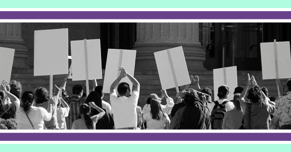Black-and-white photograph of a crowd standing outside a large stone building, holding up blank protest placards, with decorative purple and green borders above and below the image