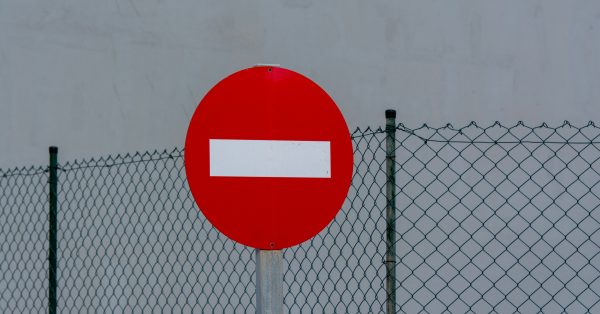 A red and white no-entry sign in front of a wire fence